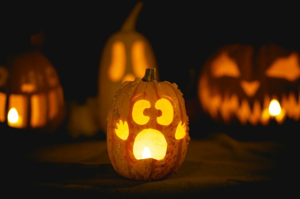 Glowing carved pumpkins with different faces lit by candles at night