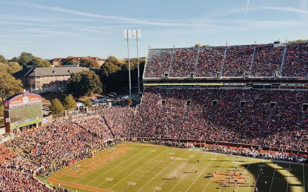 Clemson Memorial Stadium packed with orange-clad fans, painted end zone and campus buildings beyond
