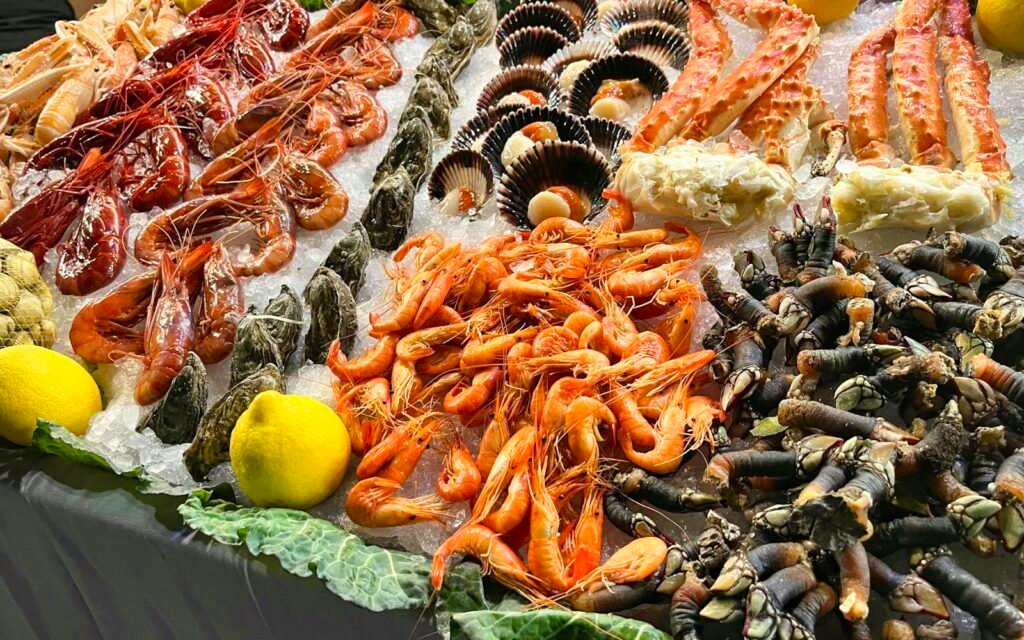 Seafood display on ice with shrimp, crab legs, scallops, clams and lemons