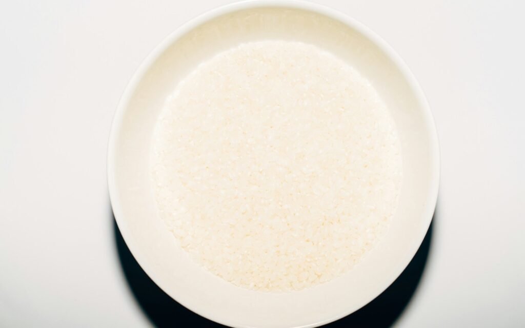 White bowl filled with fine ground white grain, seen from above on a white table