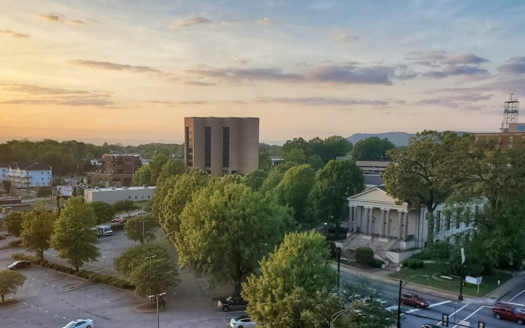 Downtown Greenville rooftops, tree-lined streets and mountains on the horizon at sunset from a parking garage