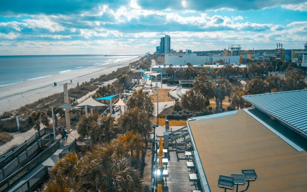 Myrtle Beach oceanfront boardwalk, palms and wide sandy beach seen from above with hotels in the distance