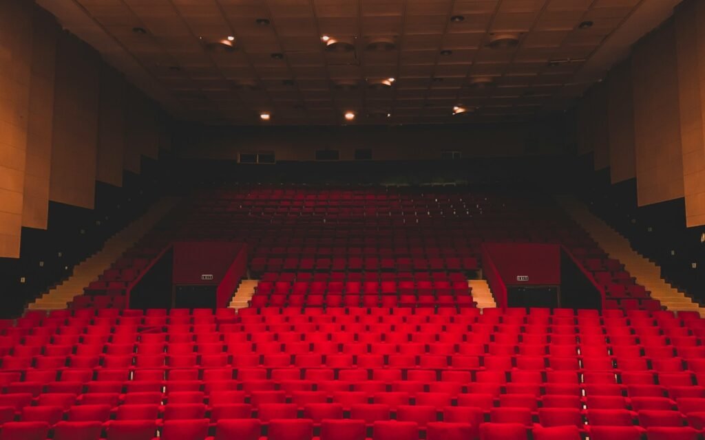 Rows of empty red seats in a dark theatre auditorium