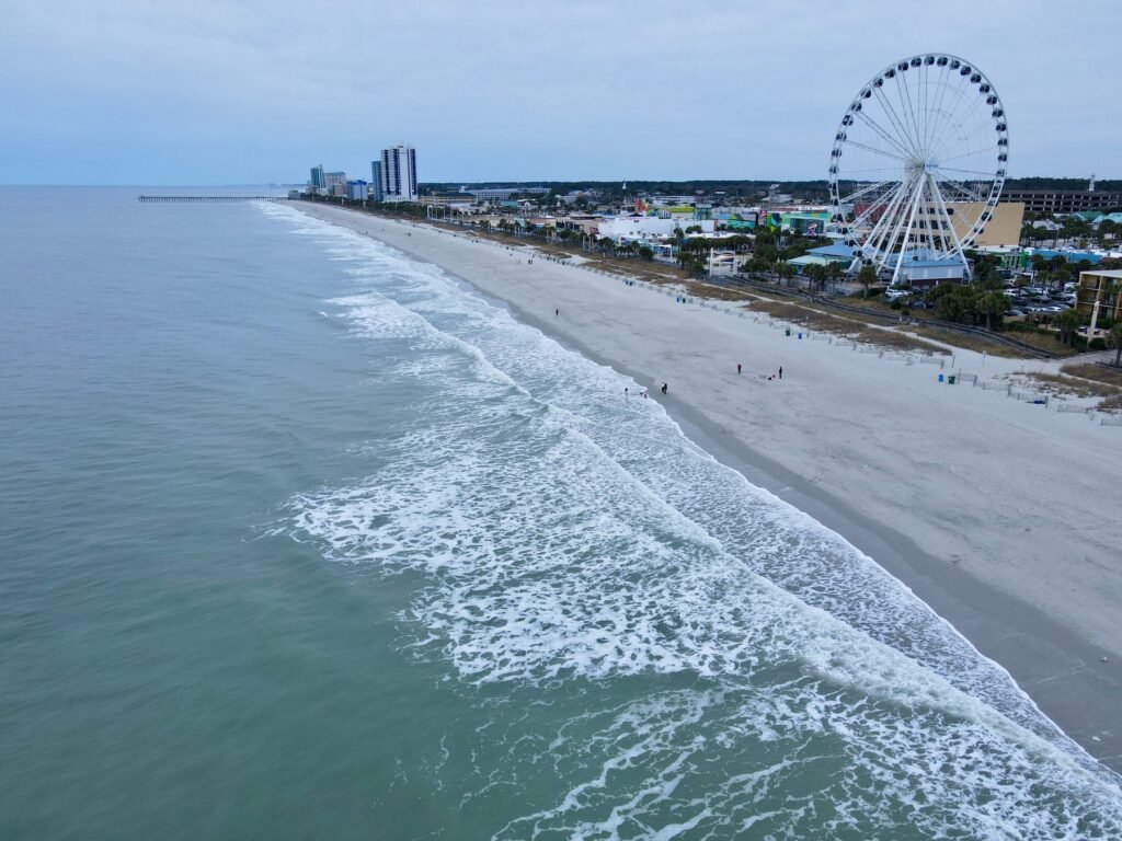 Aerial view of the Myrtle Beach shoreline with surf, the SkyWheel and hotel towers along the beach