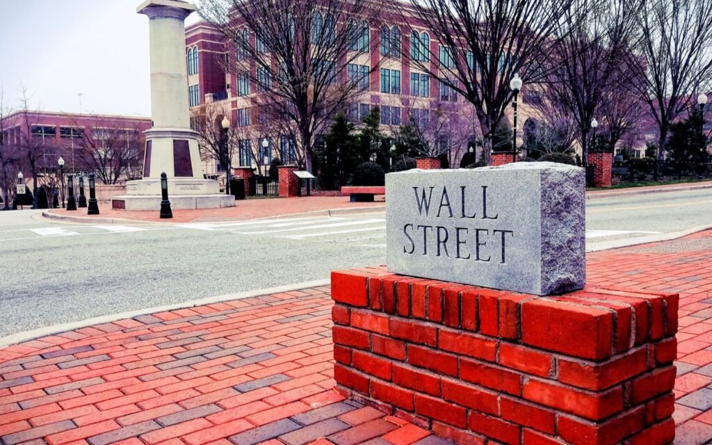 Granite Wall Street marker on a red brick base at Morgan Square with a monument column behind