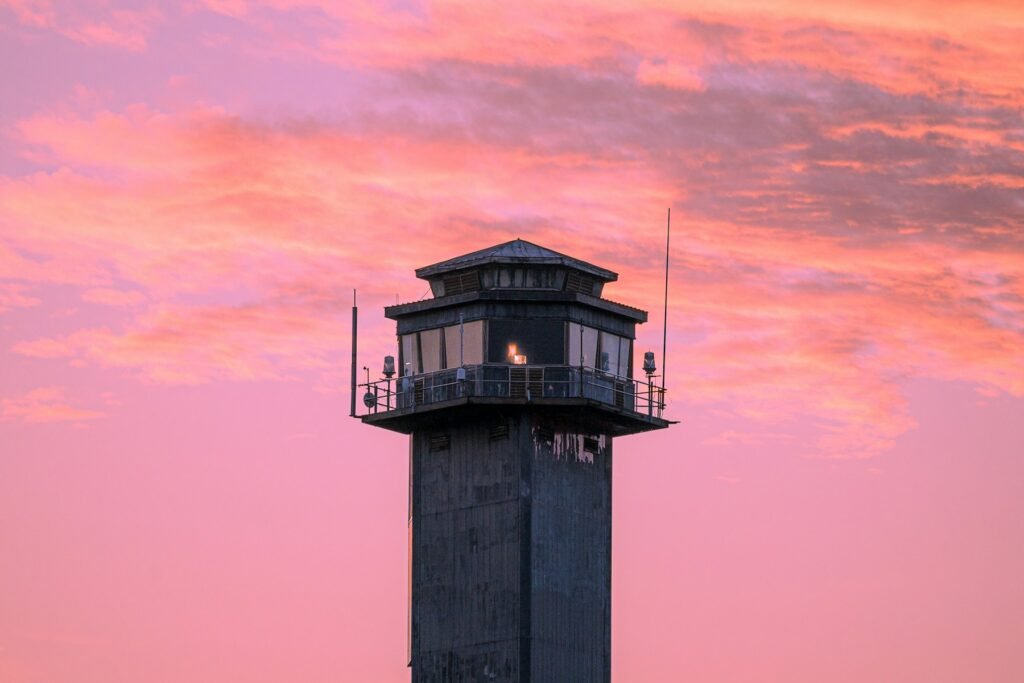 Charleston Light tower with its lantern lit against a pink and blue dusk sky