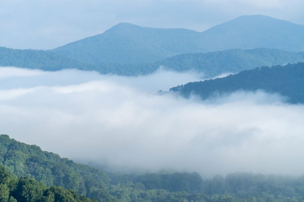 Layers of blue mountain ridges rising above a bank of low fog